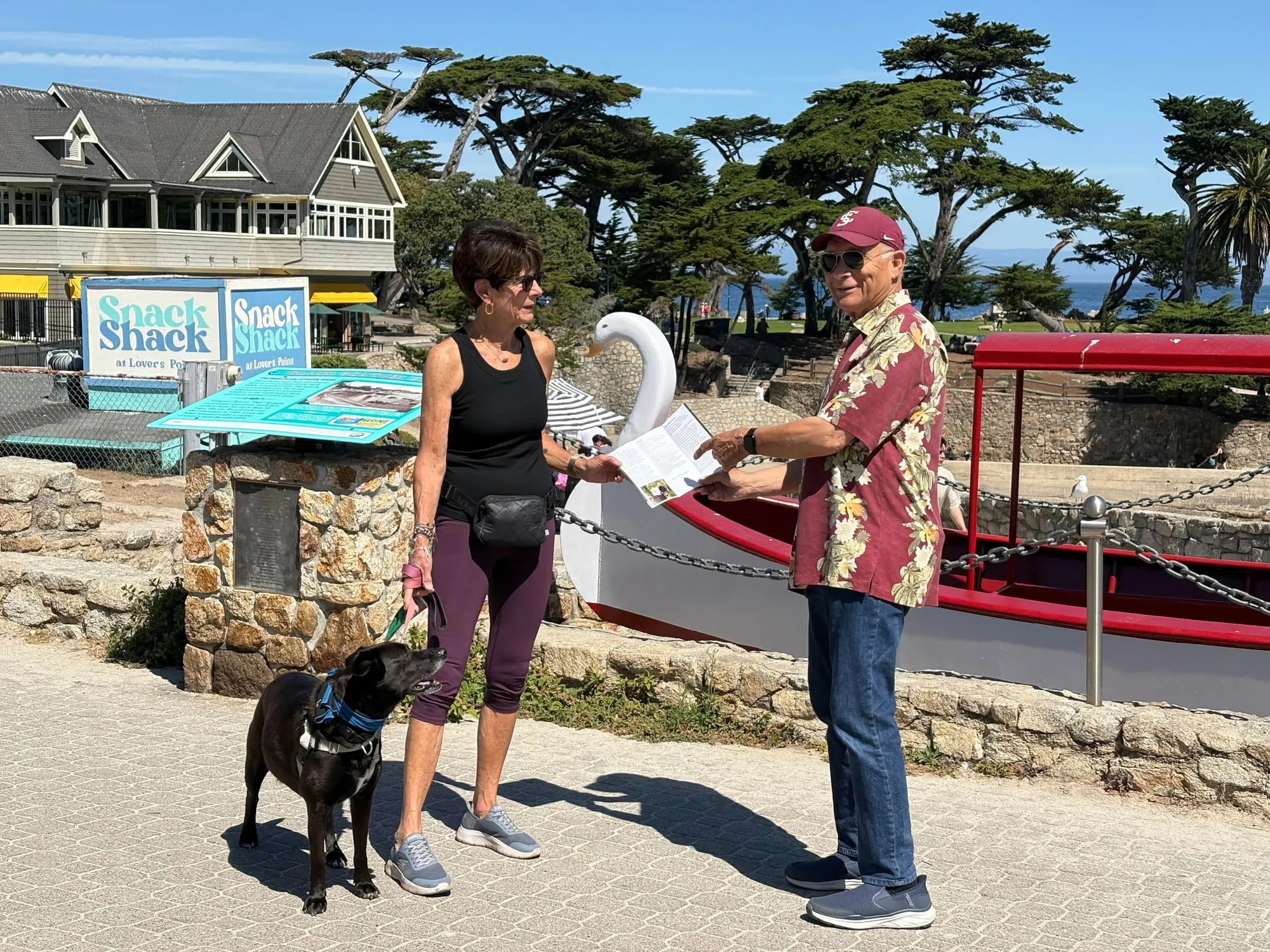 Andrew Kubica handing a campaign flyer to a resident walking her dog at Lovers Point in Pacific Grove.